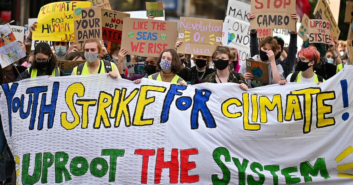 Protesters hold a banner stating "youth strike for climate! uproot the system"